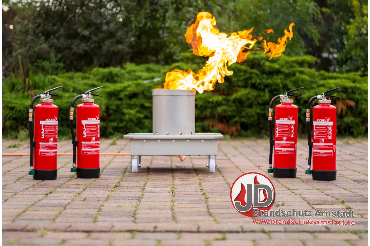 Löschübungsanlage mit kontrolliertem Feuer und vier Feuerlöschern im Freien
